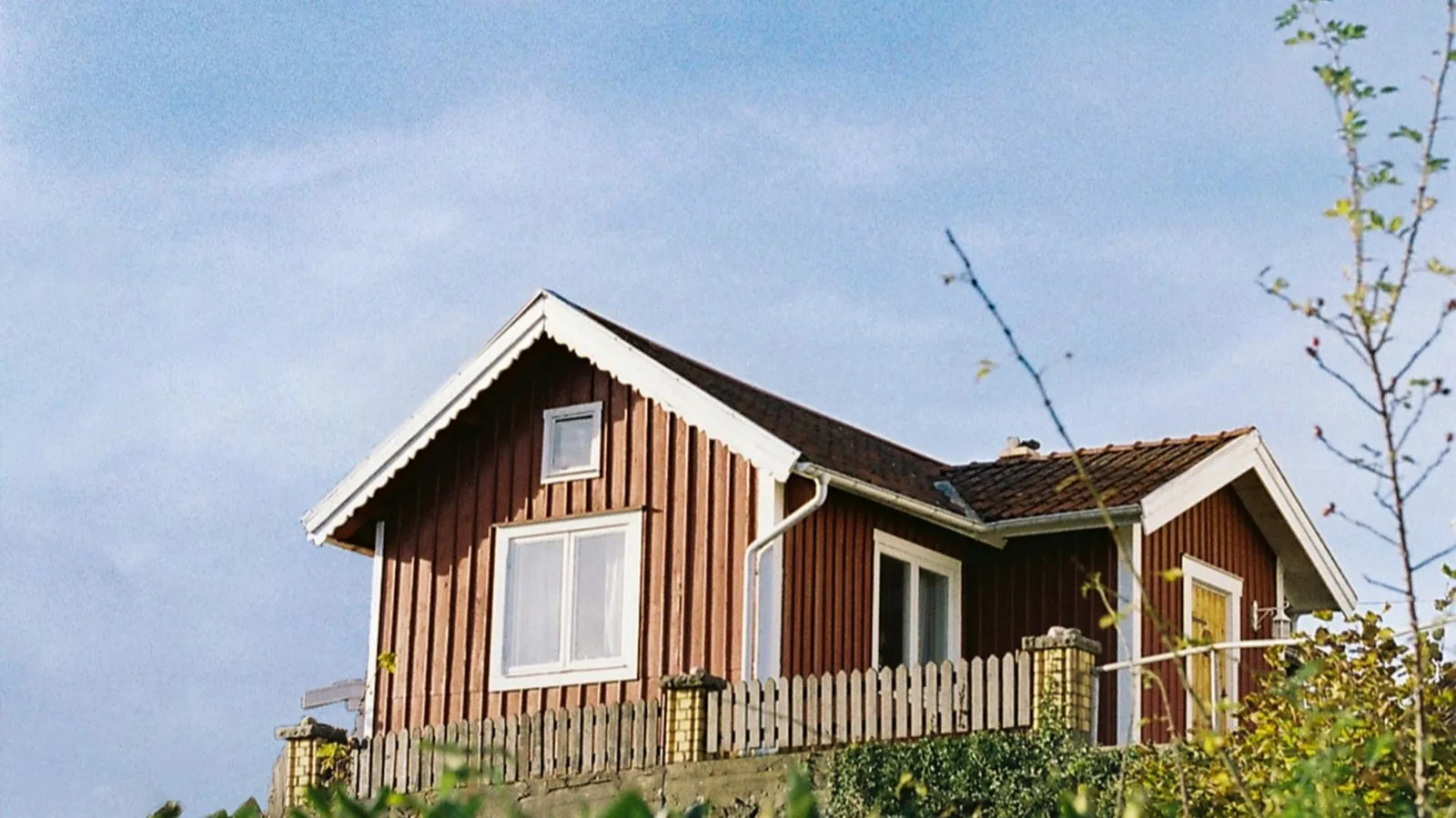 Falurött svenskt sommarhus i Långedrag mot blå himmel